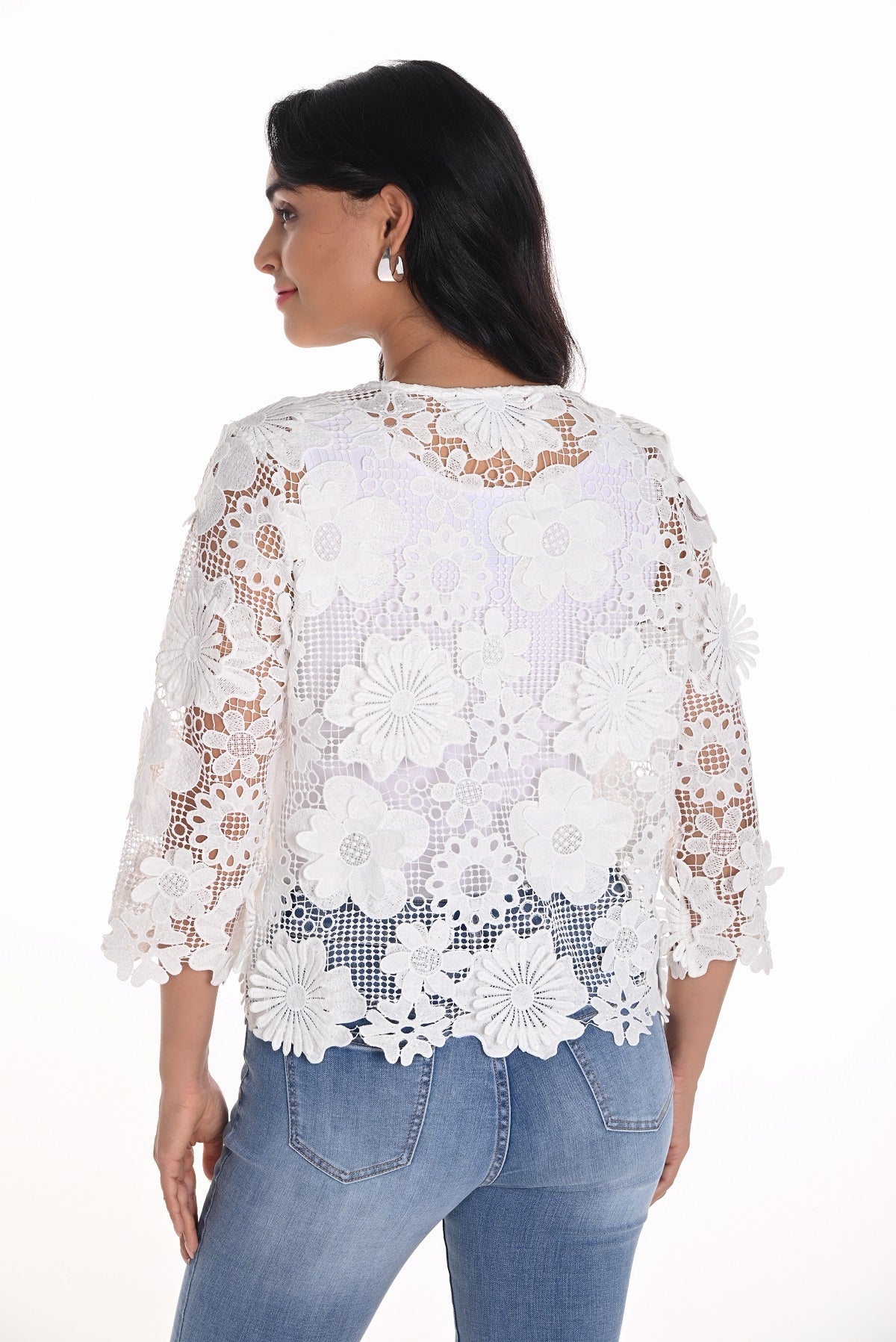 Woman wearing a white lace top and blue jeans on a white background
