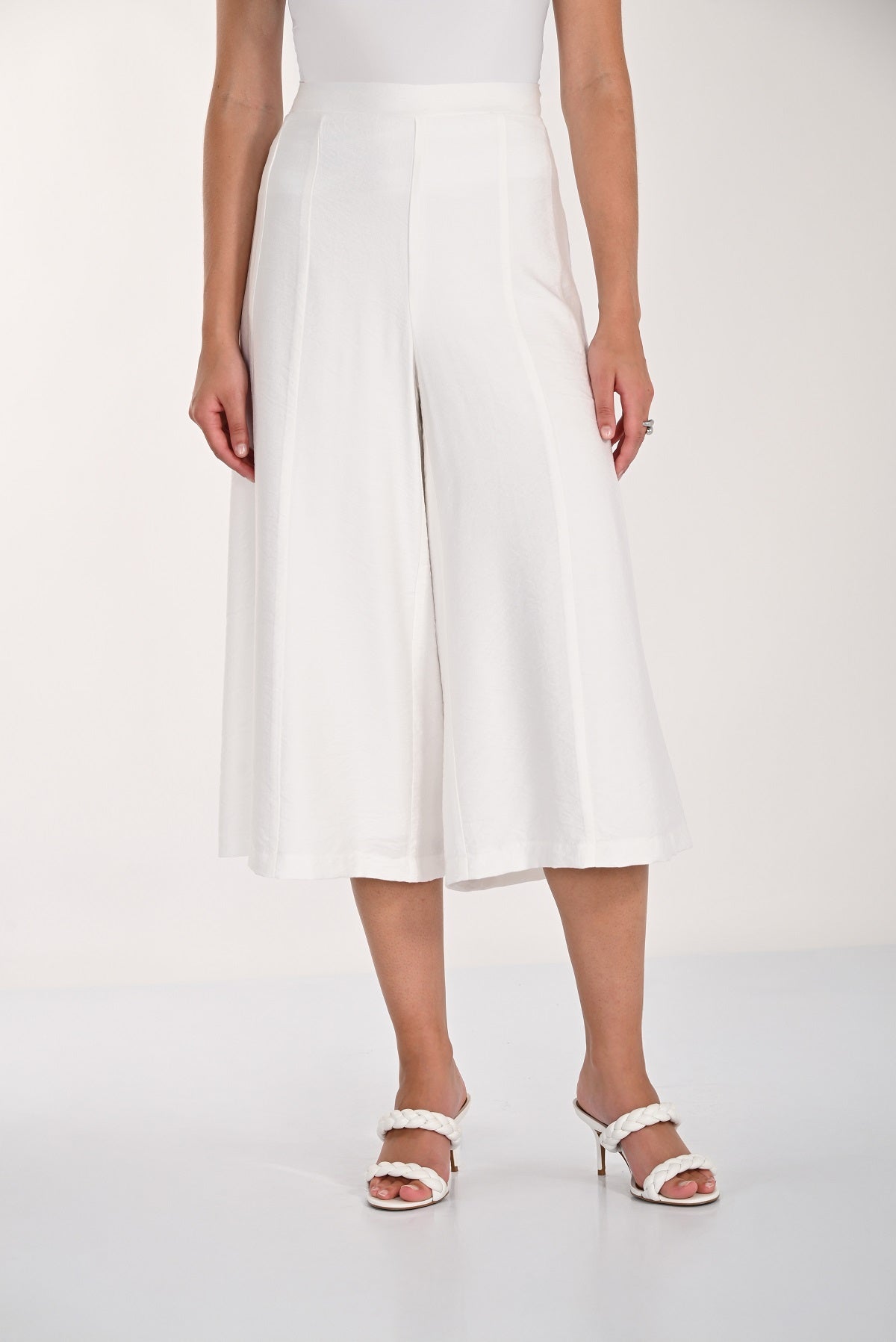 Person wearing white wide-leg pants on a plain background