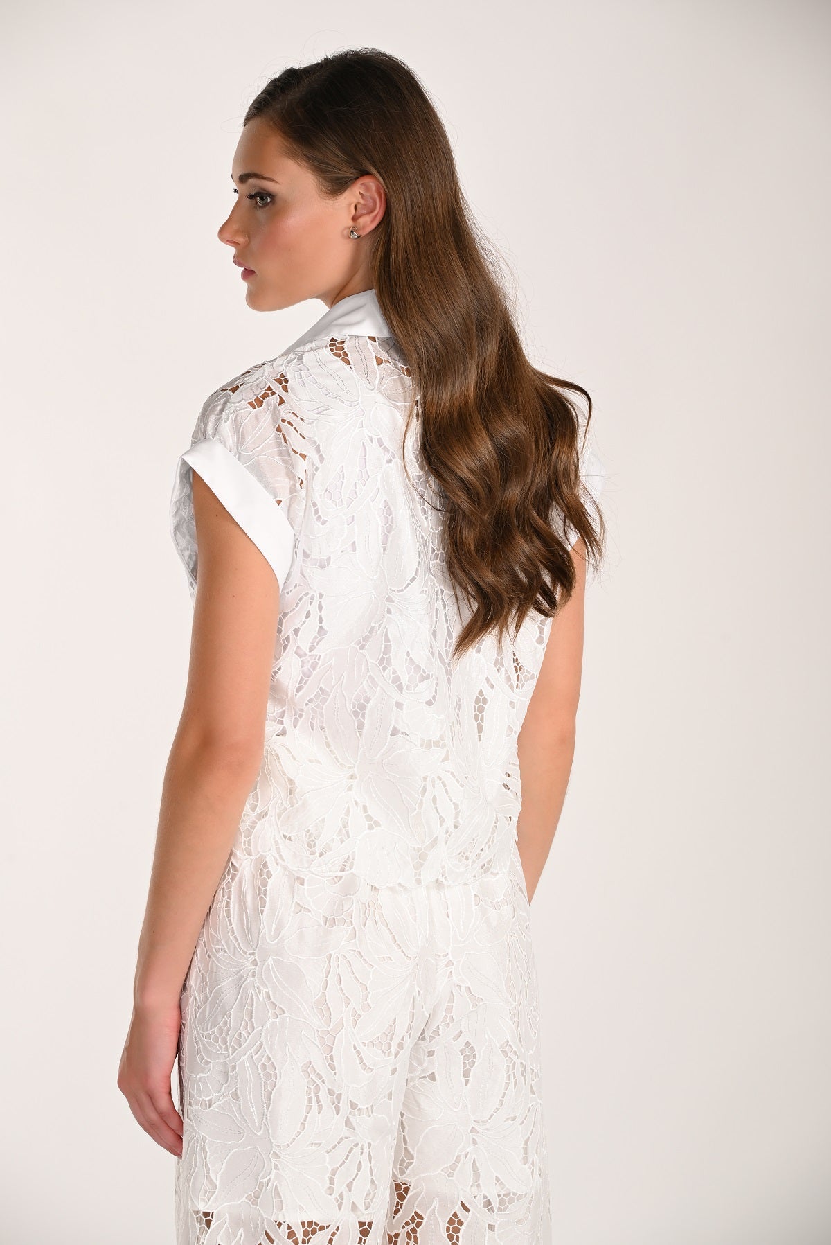 Woman wearing a white lace dress against a plain background