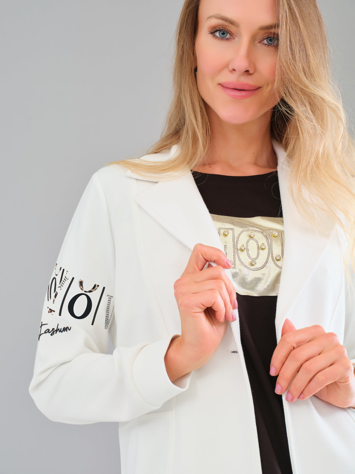 Woman wearing a white blazer with text on the sleeves against a gray background