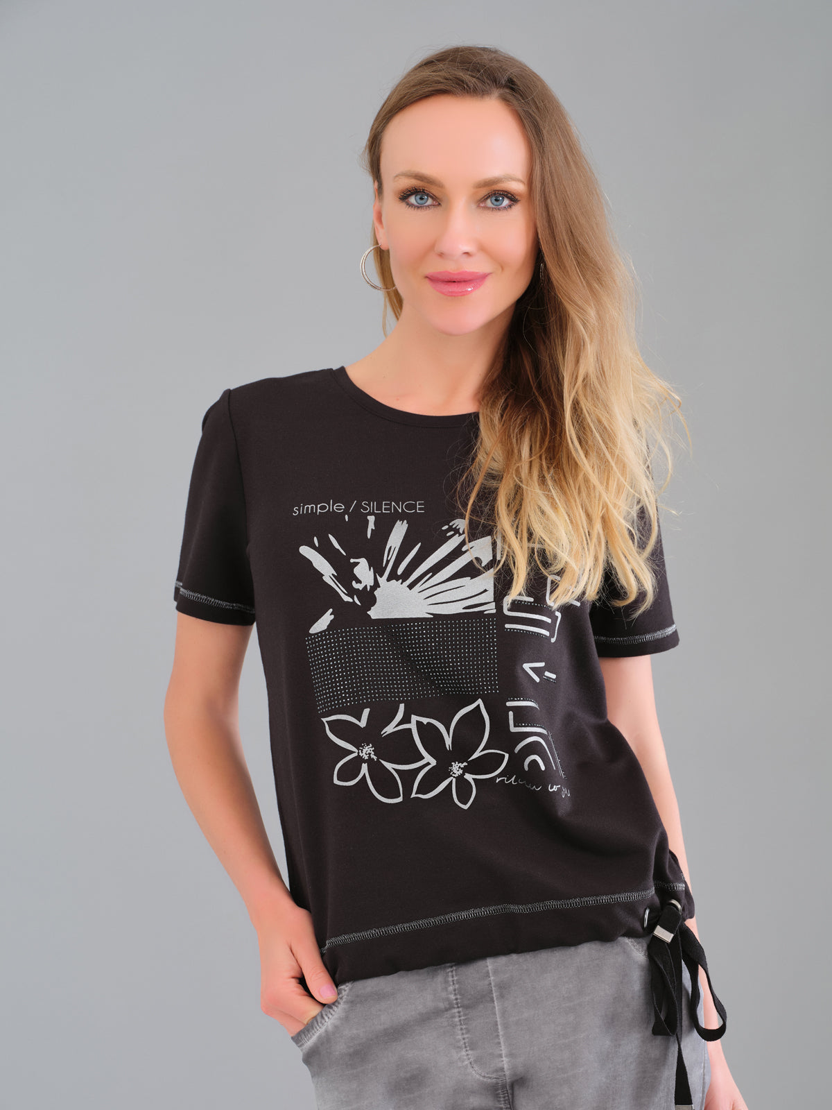 Woman wearing a black t-shirt with white graphics on a gray background