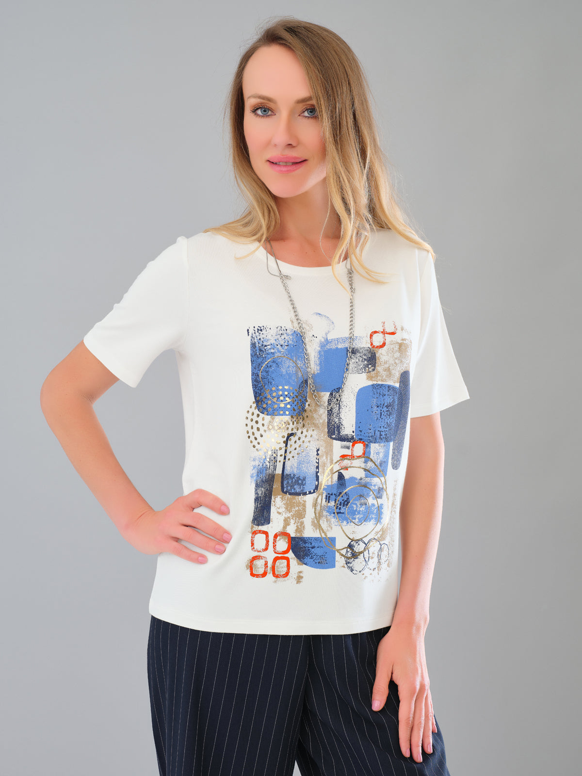 Woman wearing a white t-shirt with abstract blue and red design on a gray background