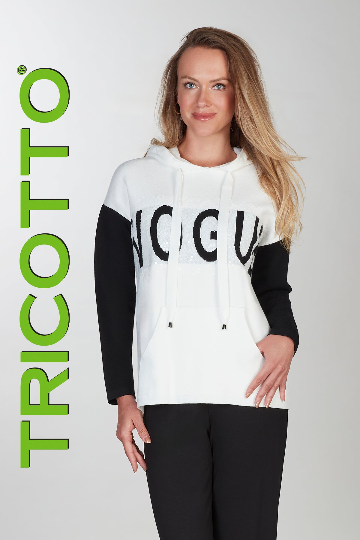 Woman wearing a white hoodie with black text and sleeves, standing against a light gray background with 'TRICOTTO' branding.