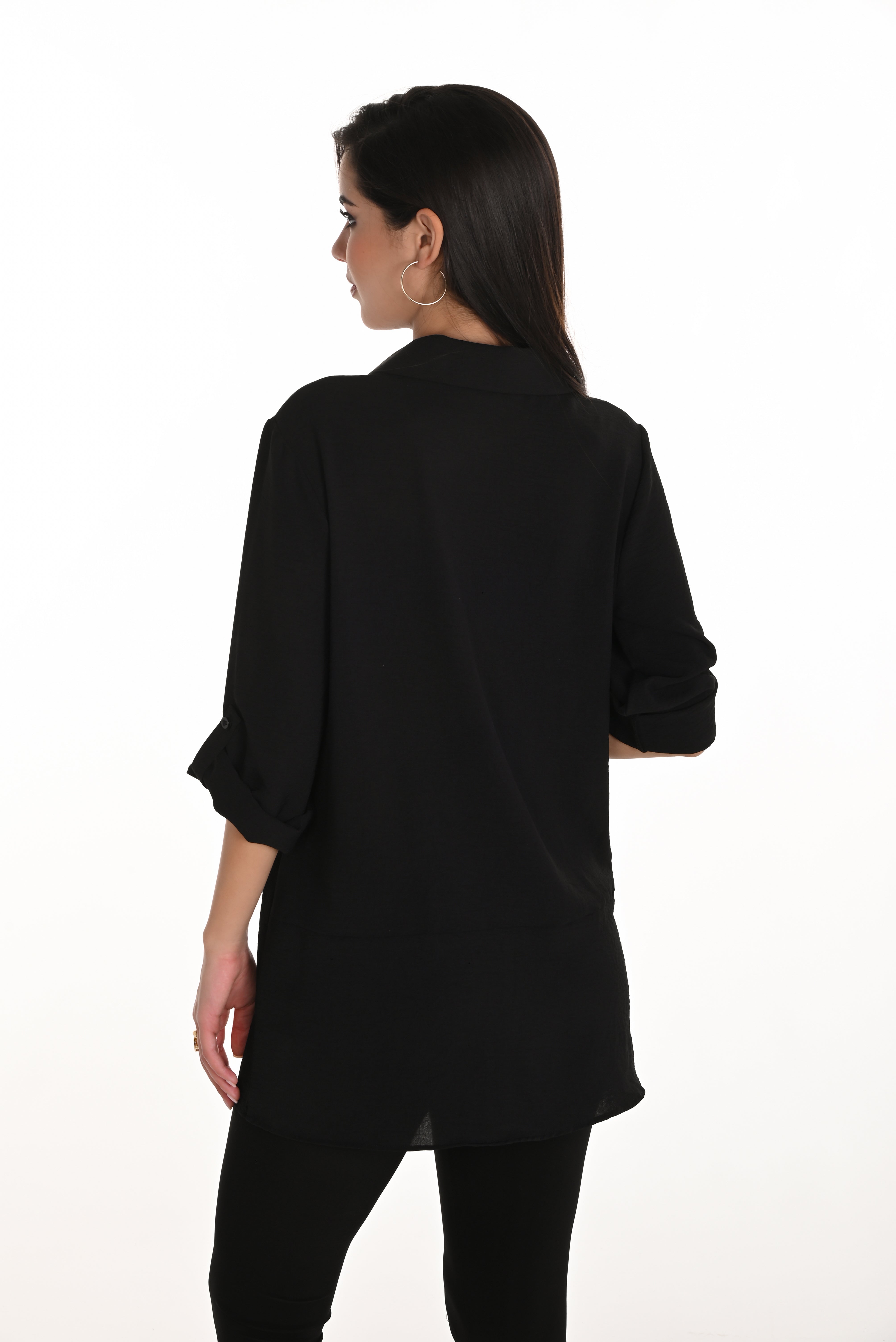 Woman wearing a black blouse with patterned patches on a white background