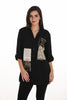 Woman wearing a black blouse with patterned patches on a white background