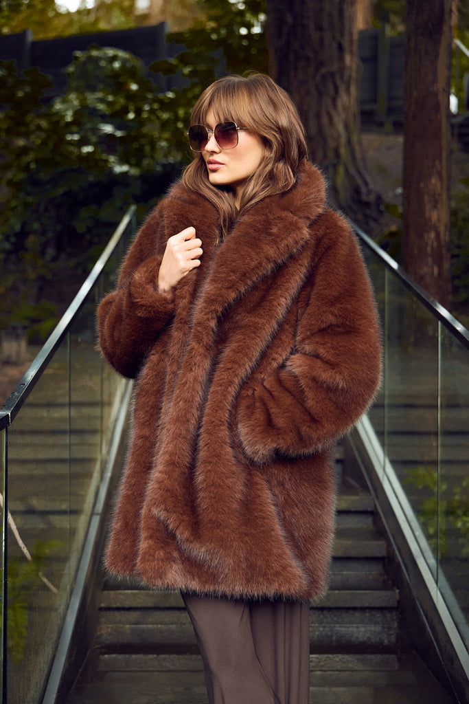 Woman wearing a brown fur coat and sunglasses on an outdoor staircase.