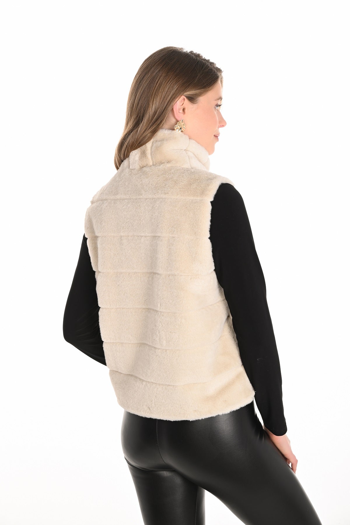 Woman wearing a beige puffer vest over a black long-sleeve shirt on a white background