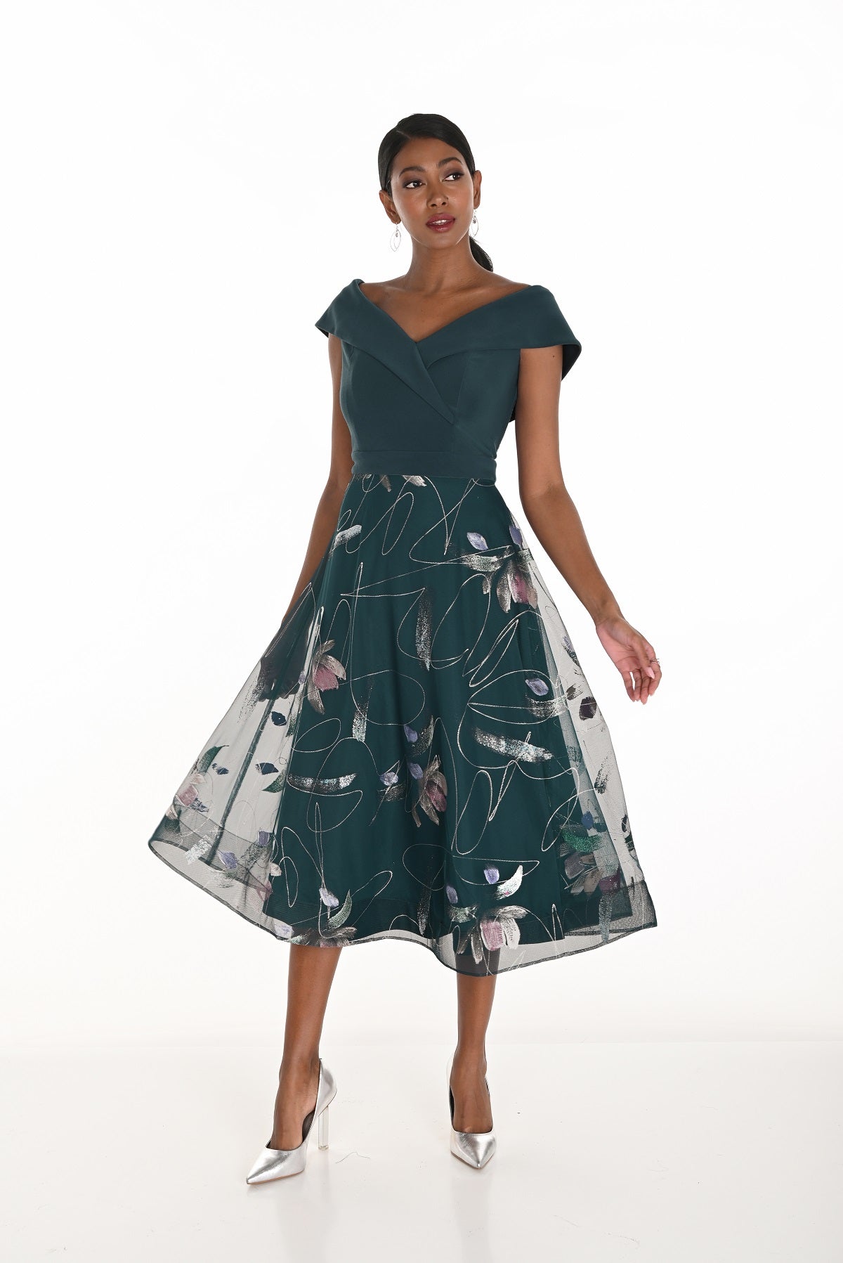 Woman wearing a dark green dress with floral pattern on a white background