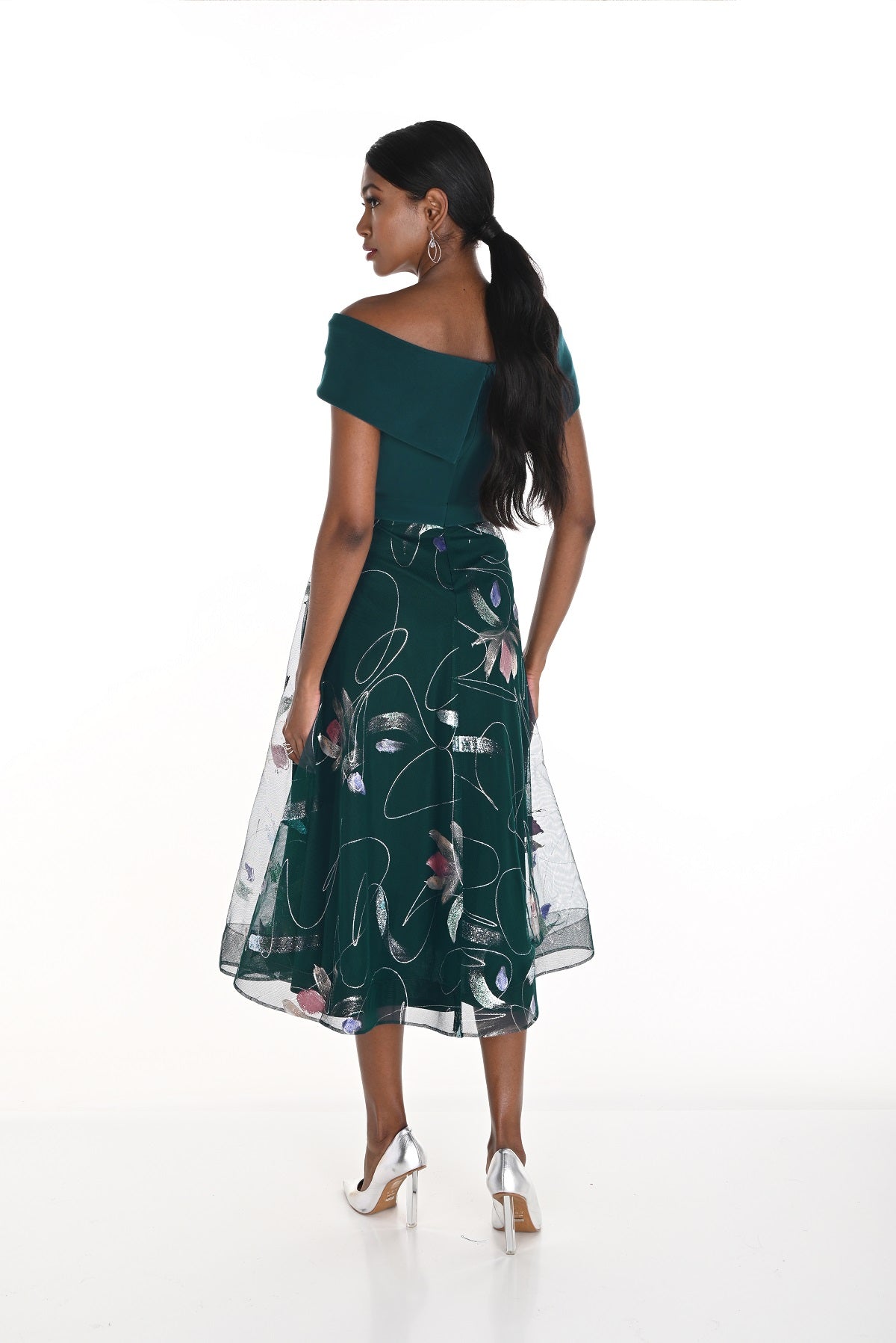 Woman wearing a dark green dress with floral pattern on a white background