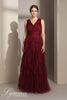 Woman wearing a burgundy evening gown with ruffled layers against a neutral background