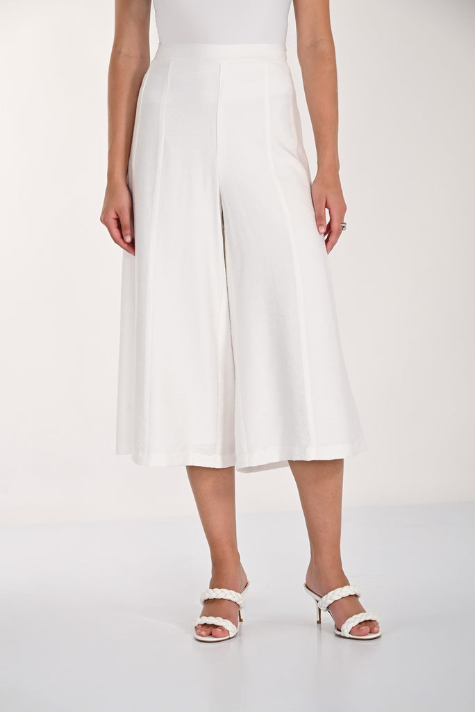 Person wearing white wide-leg pants on a plain background