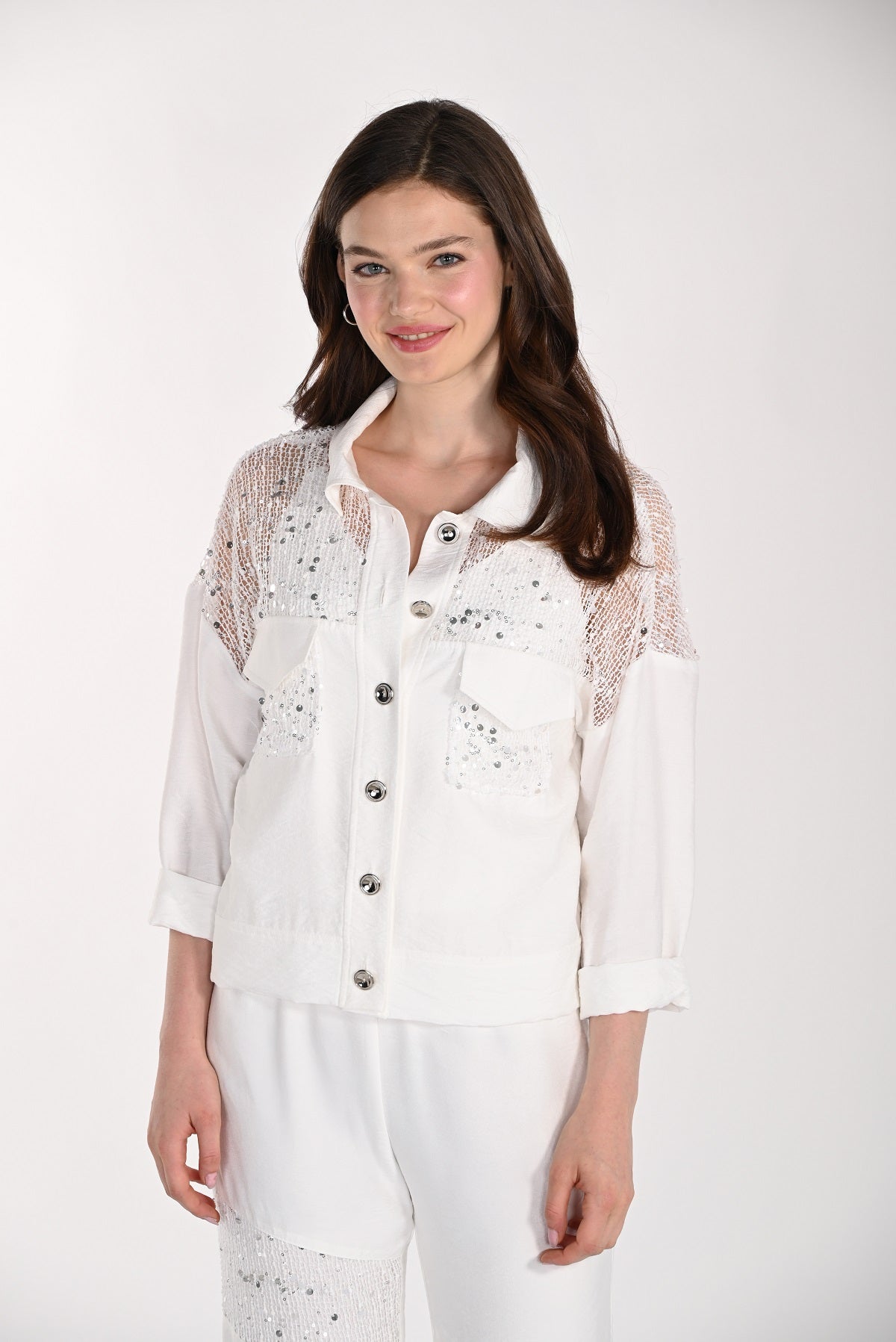 Woman wearing a white lace top with a plain background