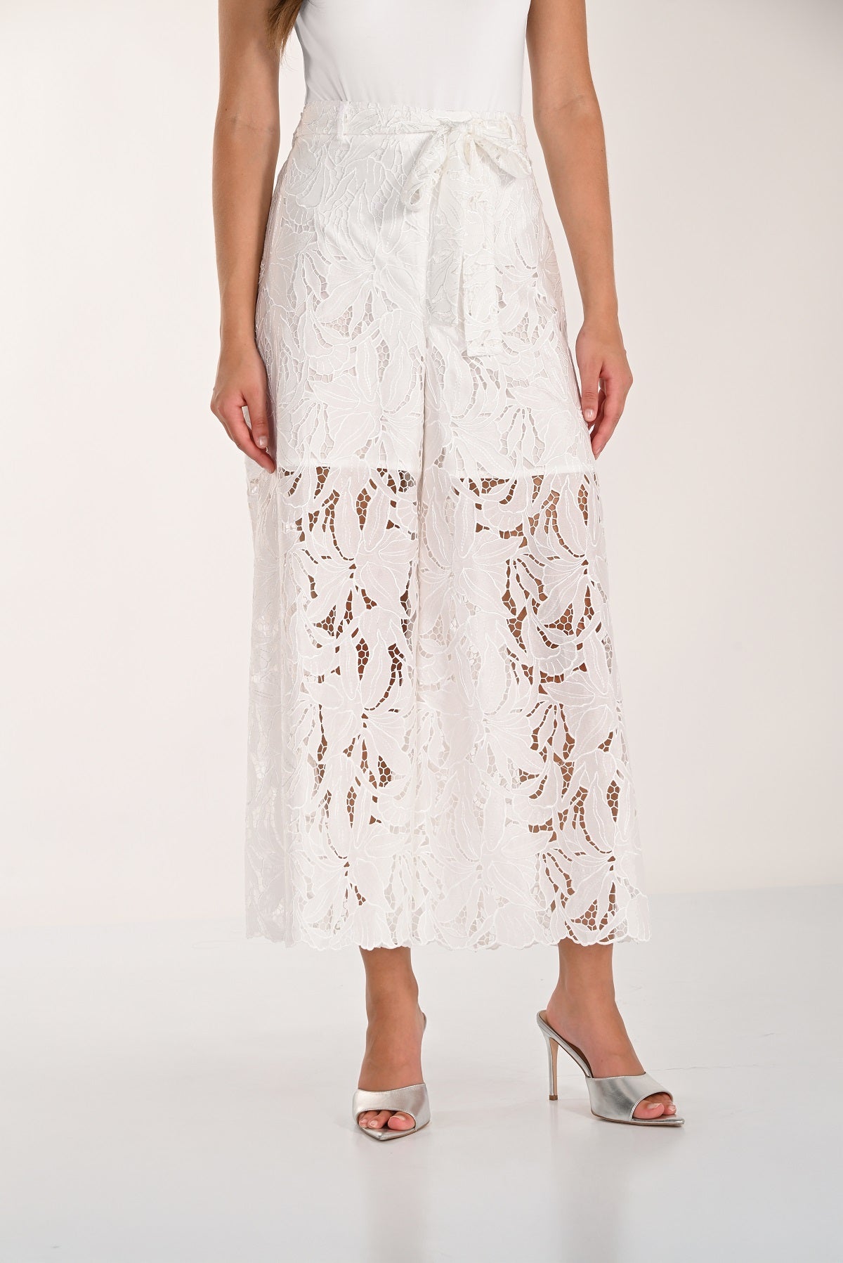 White lace pants worn by a person on a white background