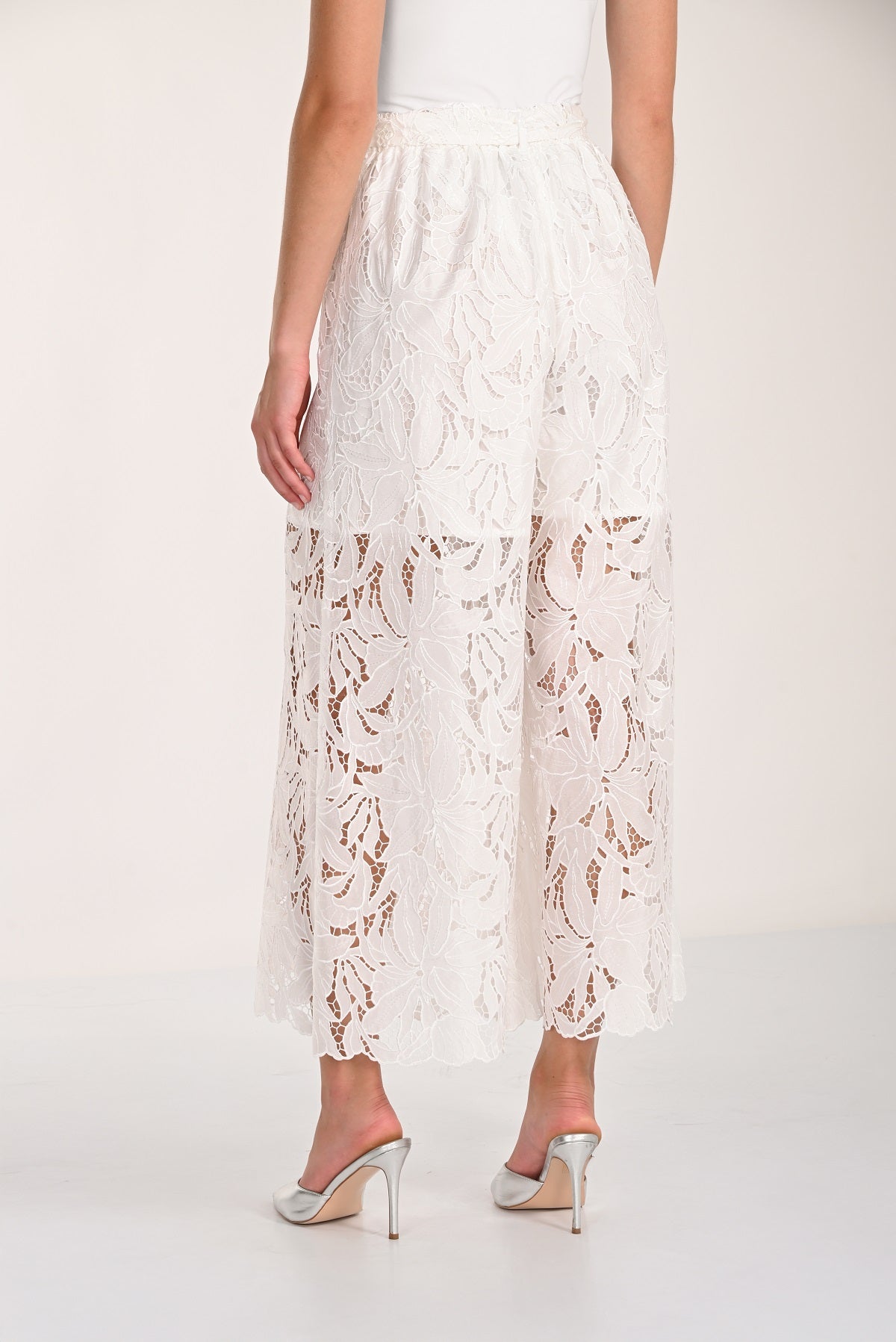 White lace pants worn by a person on a white background