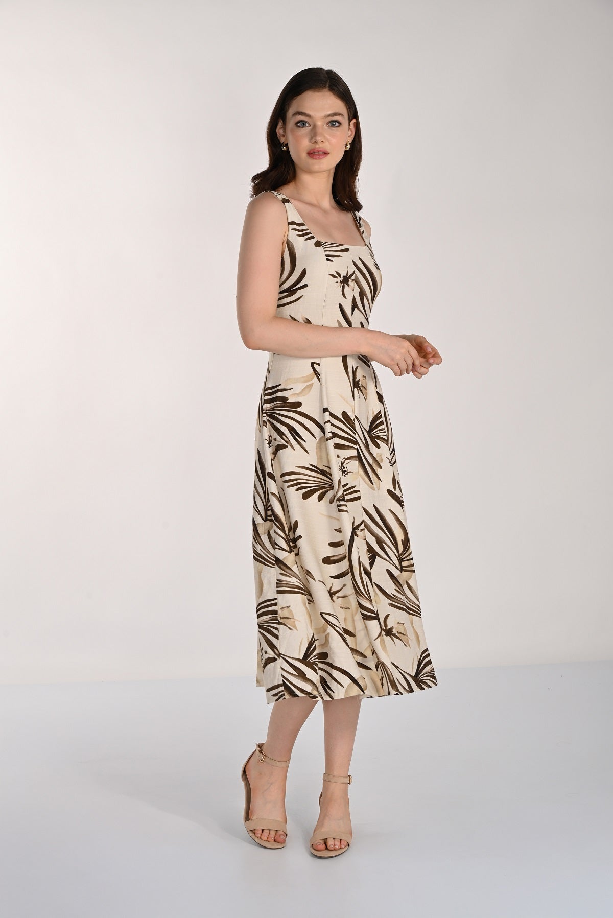 Woman wearing a sleeveless dress with a leaf pattern on a white background