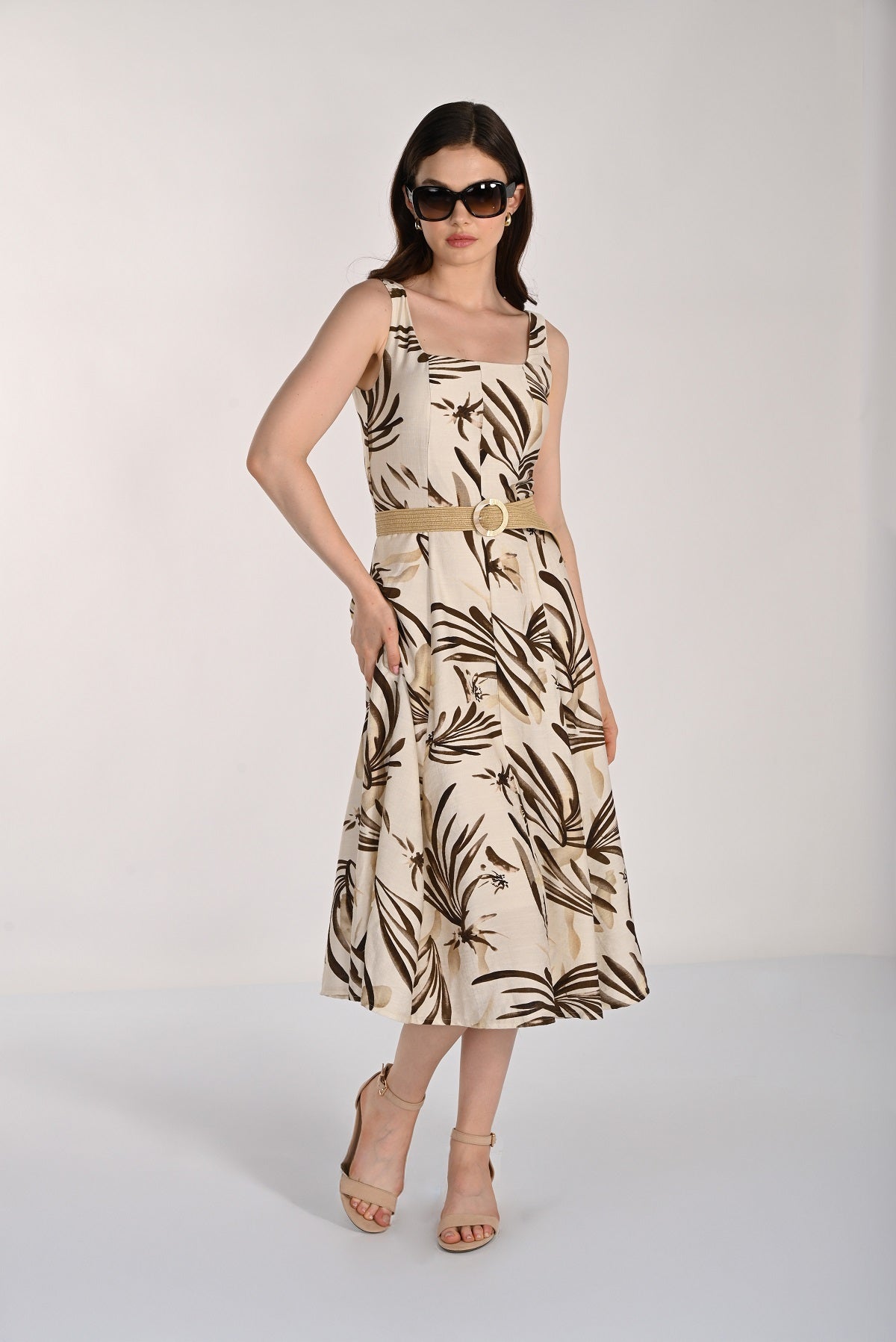 Woman wearing a sleeveless dress with leaf pattern on a white background