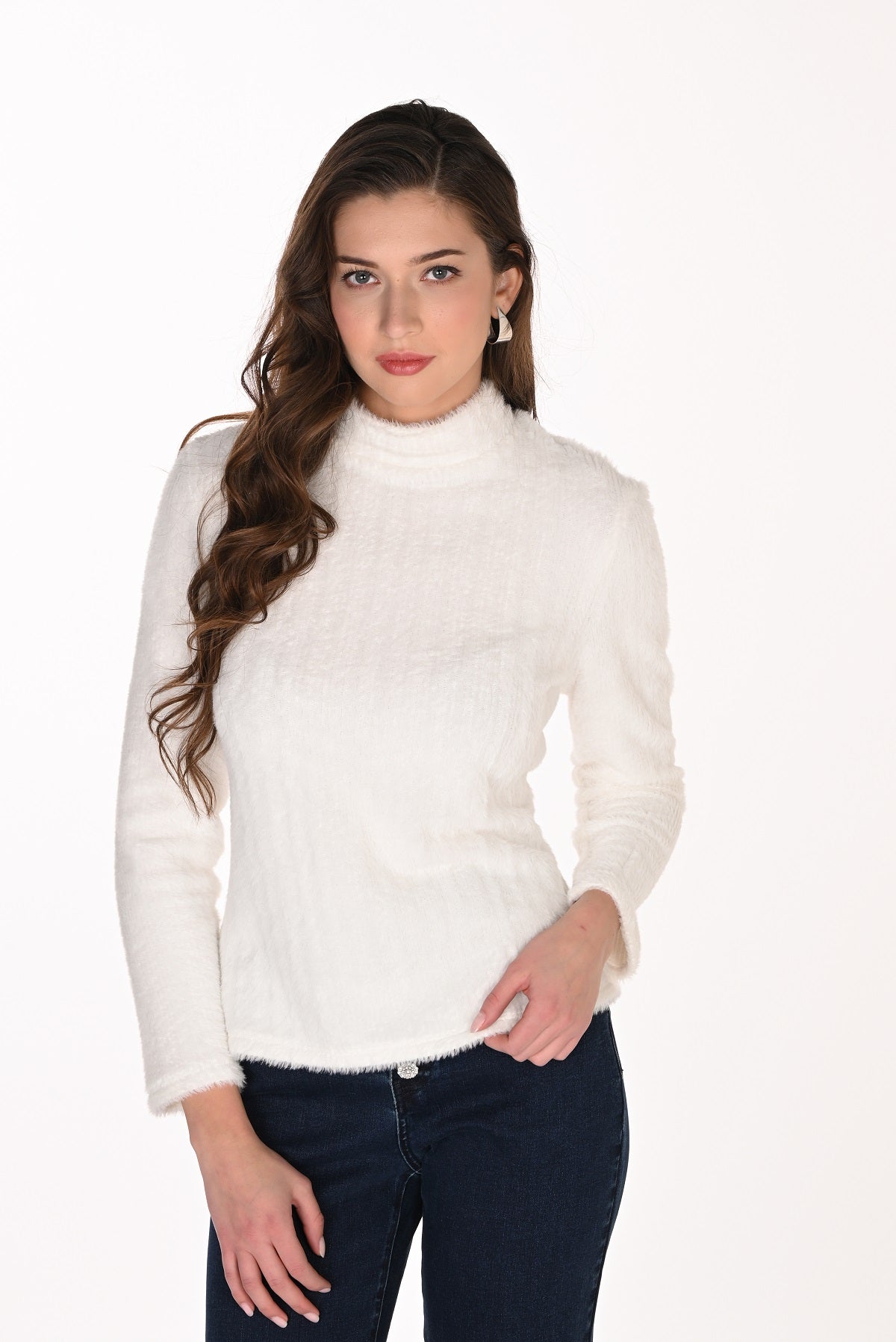 Woman wearing a white turtleneck sweater and dark jeans on a white background