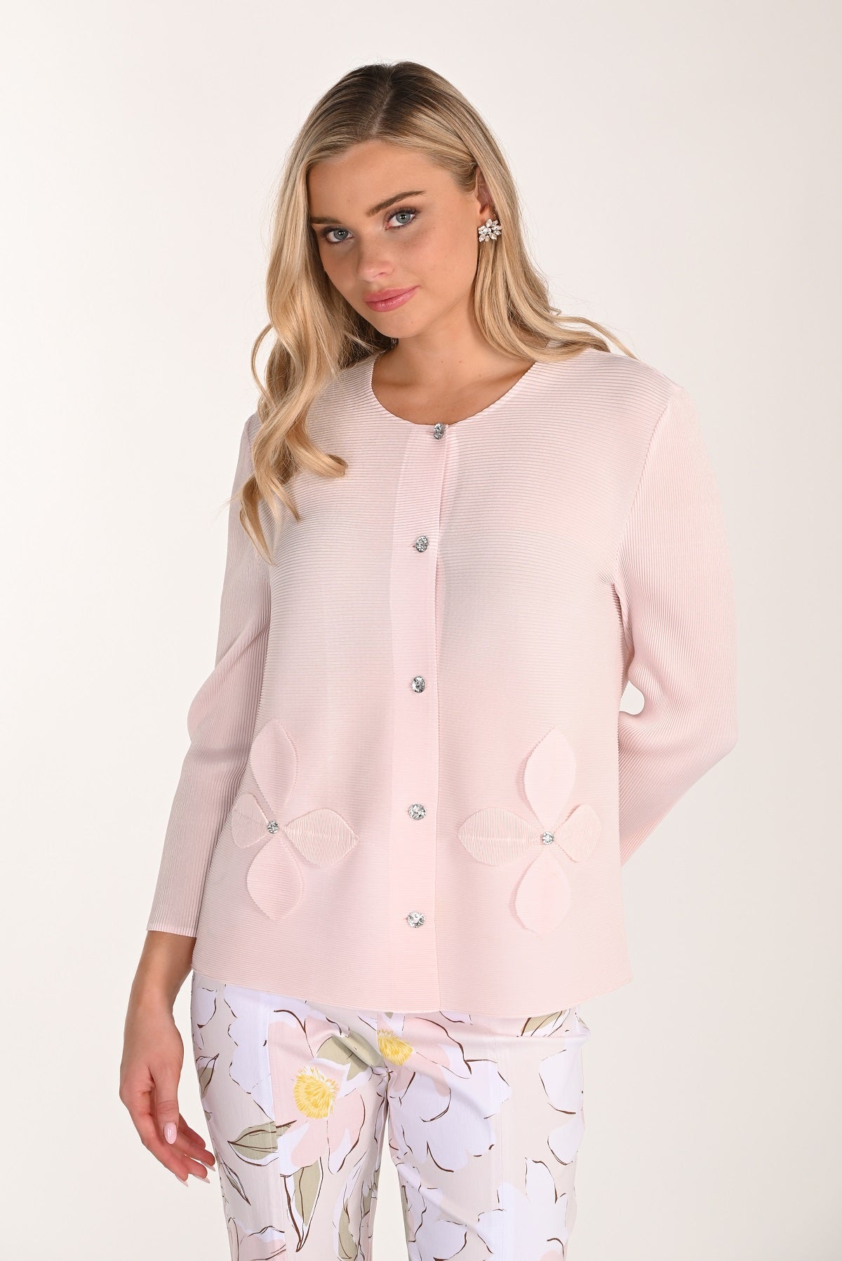 Woman wearing a light pink cardigan over a floral dress on a white background