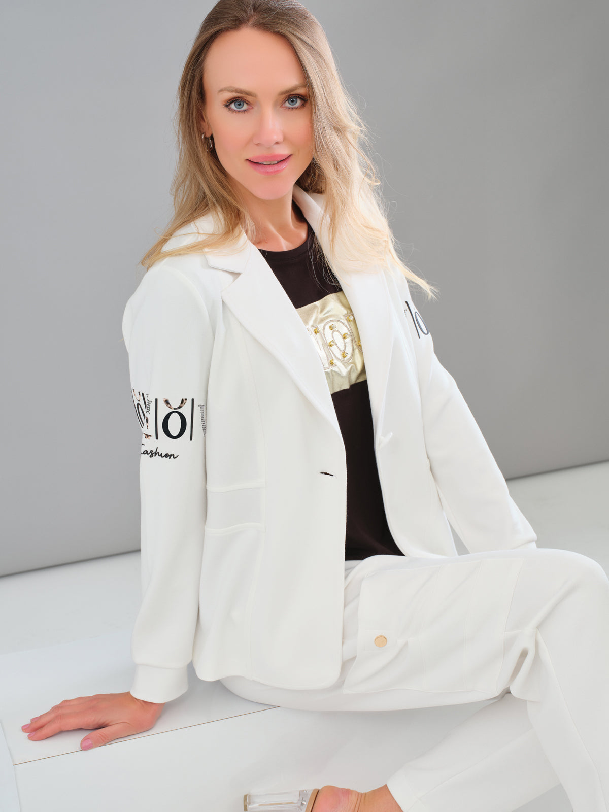 Woman wearing a white outfit with visible branding on a gray background