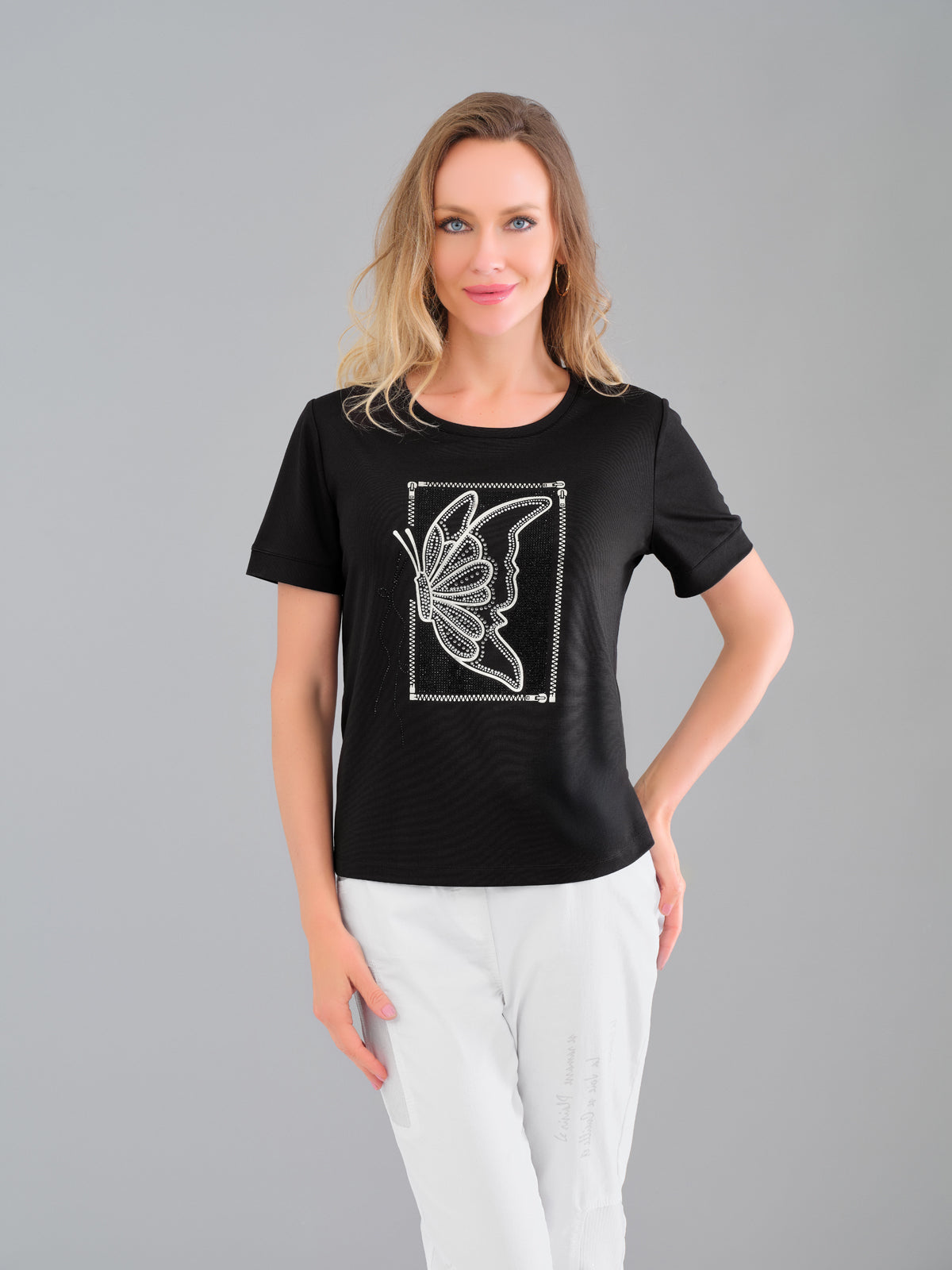 Woman wearing a black t-shirt with a butterfly design on a gray background