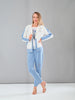 Woman wearing a light blue denim outfit with a white jacket against a gray background