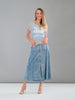 Woman wearing a striped shirt and denim skirt against a gray background