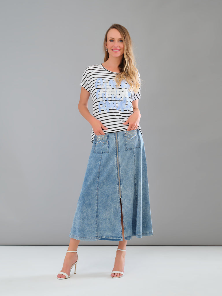 Woman wearing a striped shirt and denim skirt against a gray background