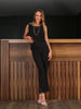 Woman in black outfit standing against a wooden wall