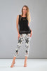 Woman wearing a black sleeveless top and floral capri pants on a gray background