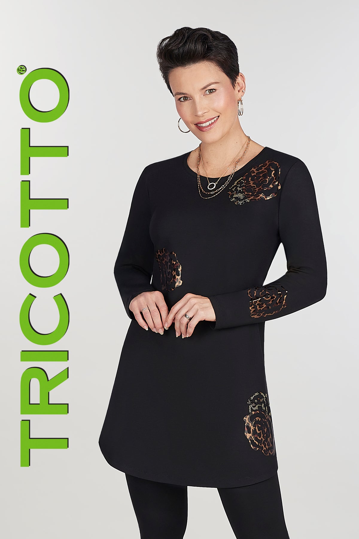 Woman wearing a black dress with leopard print details, standing against a white background with 'Tricotto' branding.