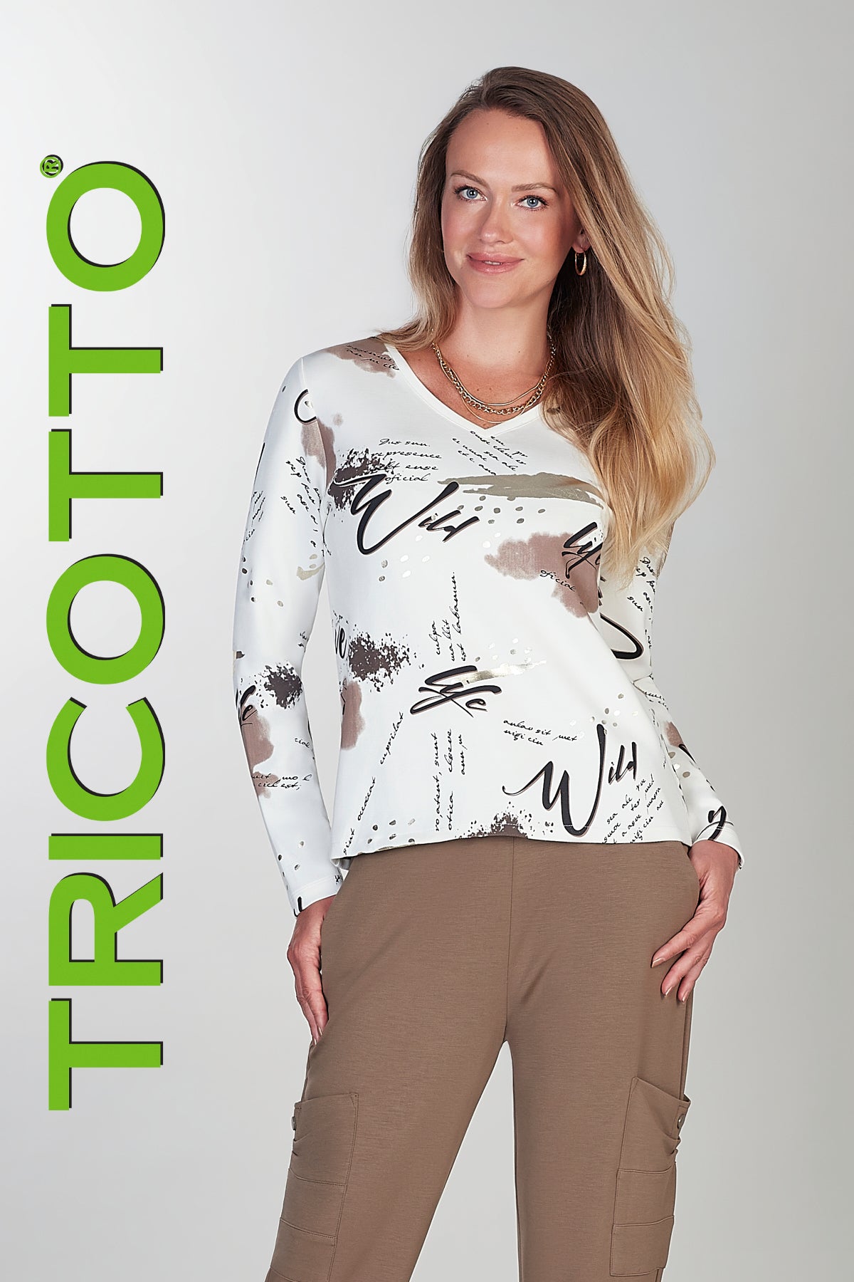 Woman wearing a long-sleeve top with graphic design and cargo pants, standing against a plain background with 'TRICOTTO' branding.