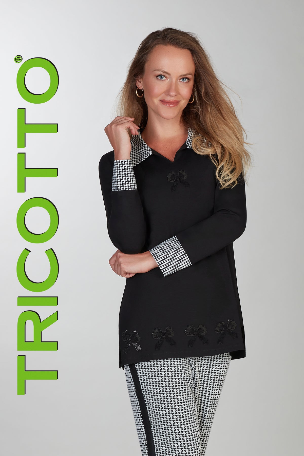 Woman wearing a black top with checkered details, standing against a white background with 'TRICOTTO' branding.