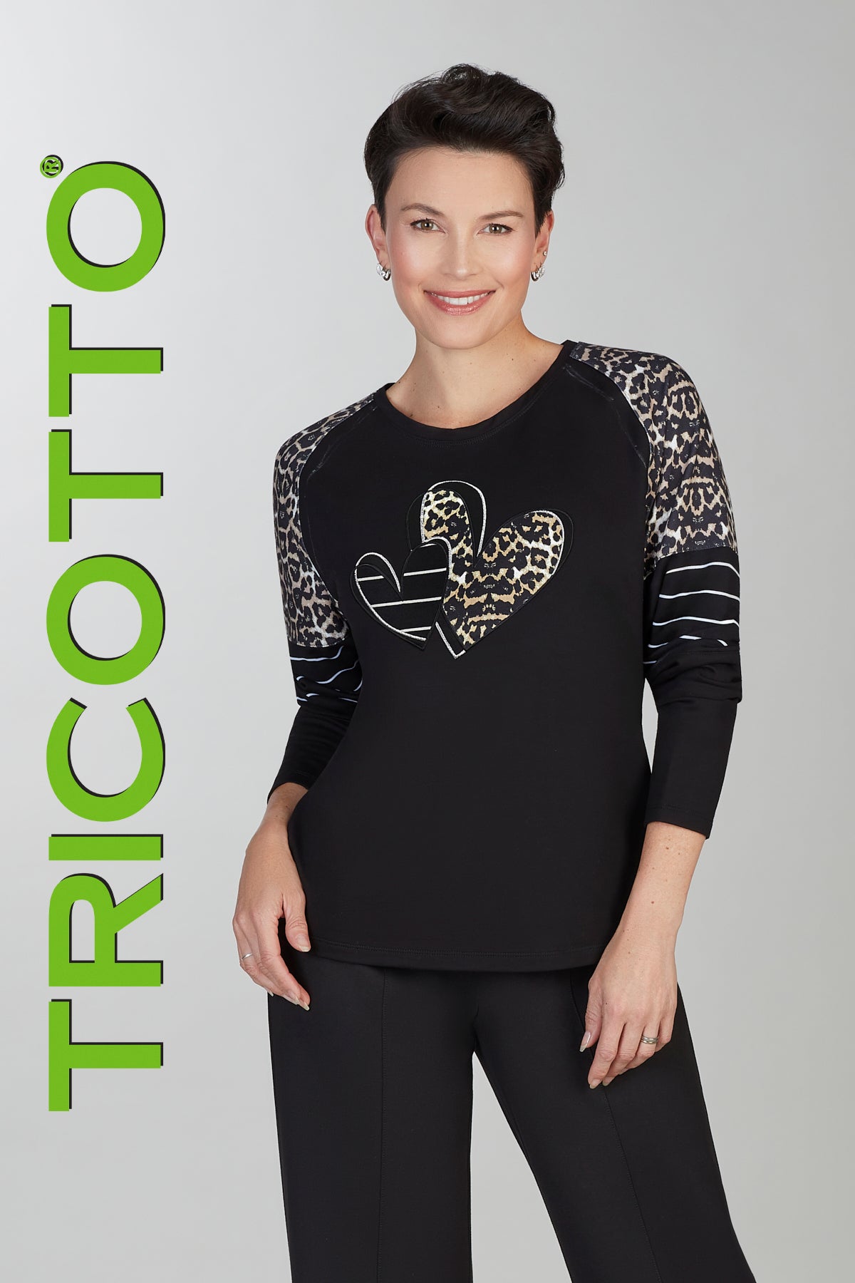 Woman wearing a black outfit with patterned sleeves, standing against a gray background with 'TRICOTTO' branding.