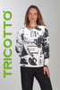 Woman wearing a black and white patterned long-sleeve shirt with 'TRICOTTO' branding on a gray background.
