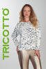 Woman wearing a patterned top and metallic pants with 'Tricotto' branding on a white background