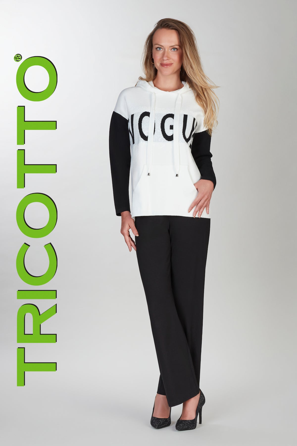 Woman wearing a black and white outfit with 'TRICOTTO' branding on a gray background