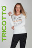 Woman wearing a white sweater with graphics and black pants, standing against a plain background with 'TRICOTTO' branding.