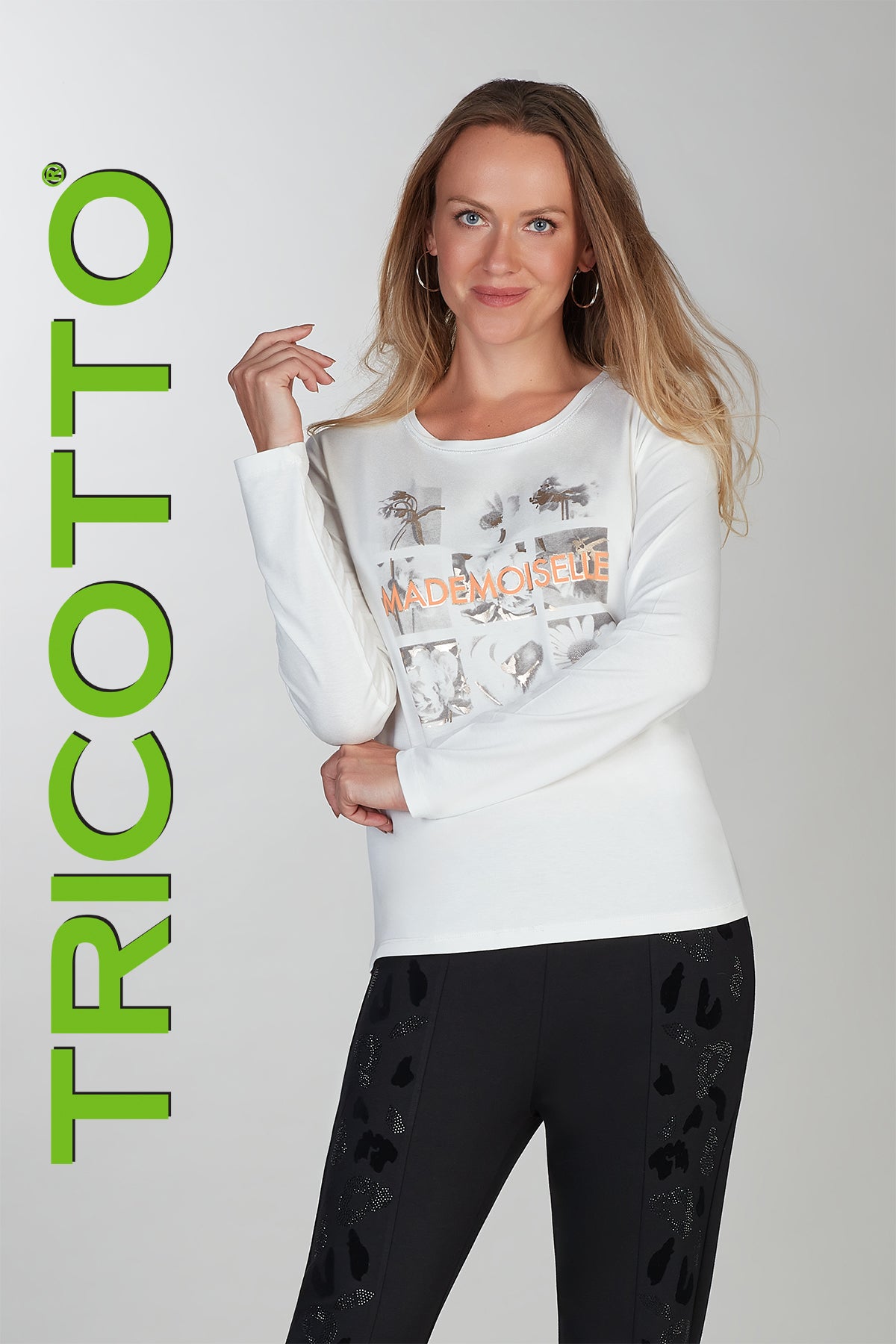 Woman wearing a white sweater with graphics and black pants, standing against a plain background with 'TRICOTTO' branding.